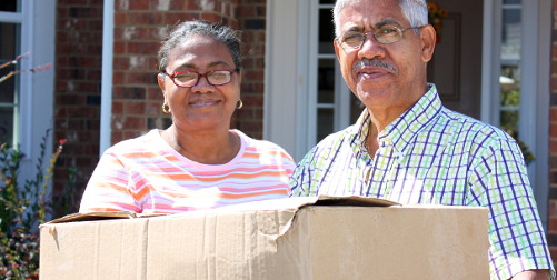 moving to a state without income tax ; image- older couple with moving box in front of house