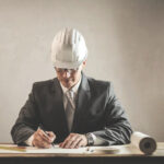 Milestones for Federal Employees ; image: man wearing hardhat at the drawing board