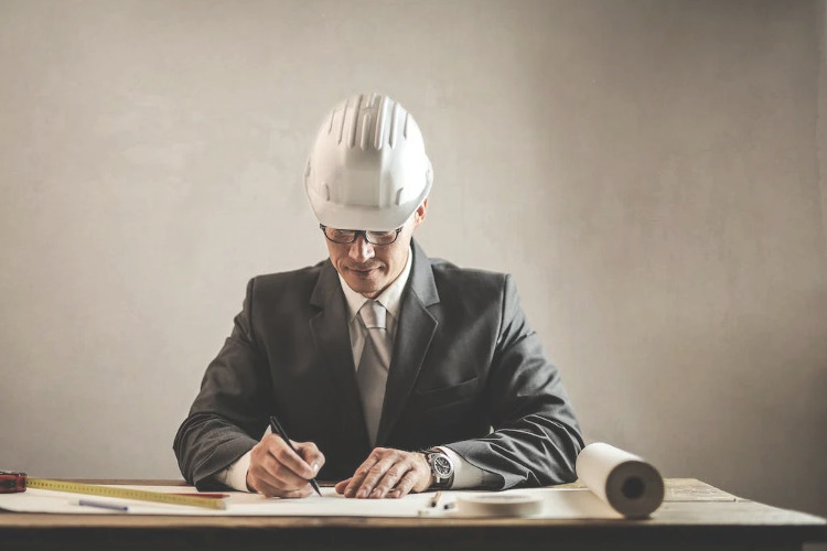Milestones for Federal Employees ; image: man wearing hardhat at the drawing board