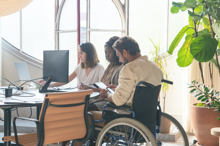 Disability Retirement Rules - image: working in a wheelchair with coworkers