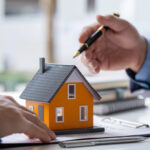estate planning for federal employees ; image: hand holding pen over house model
