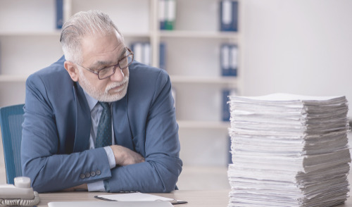 OPM Backlog of Retirement Claims ; image: Man looking at stack of papers on a desk