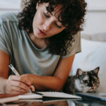 FEGLI Life Insurance Assignment ; image: woman writing in a journal with her cat