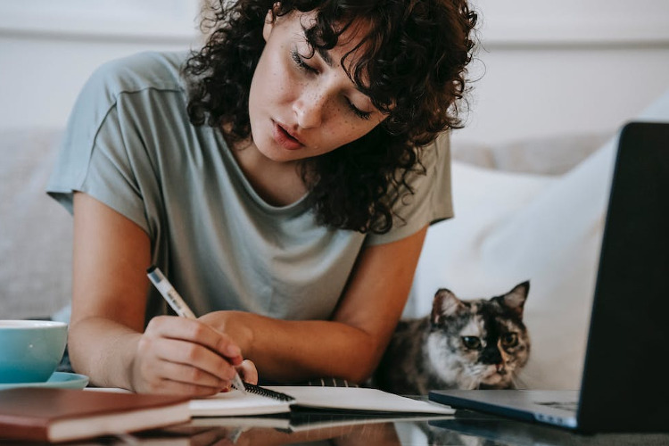 FEGLI Life Insurance Assignment ; image: woman writing in a journal with her cat