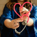 FEHB Open Season Webinar ; image: woman holding a heart stethoscope